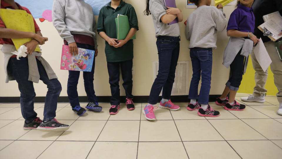 FILE - In this Aug. 29, 2019, file photo, migrant teens line up for a class at a "tender-age" facility for babies, children and teens, in Texas' Rio Grande Valley, in San Benito, Texas. A federal volunteer at the Biden administration's largest shelter for unaccompanied immigrant children says paramedics were called regularly during her the two weeks she worked there. She said panic attacks would occur often after some of the children were taken away to be reunited with their families, dashing the hopes of those left behind. The conditions described by the volunteer highlight the stress of children who cross the U.S.-Mexico border alone and now find themselves held at unlicensed mass-scale facilities waiting to reunite with relatives. (AP Photo/Eric Gay File)