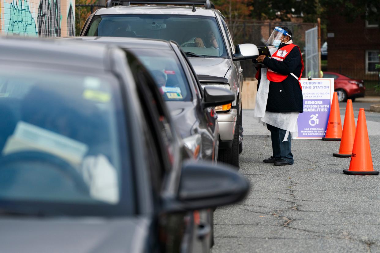 Poll worker Sheila Thomas helps voters to submit their ballots from the curbside voting line, Tuesday, Oct. 27, 2020, at Malcolm X Opportunity Center, an early voting center in Washington. Curbside voting is offered at this location for seniors and people with disabilities.