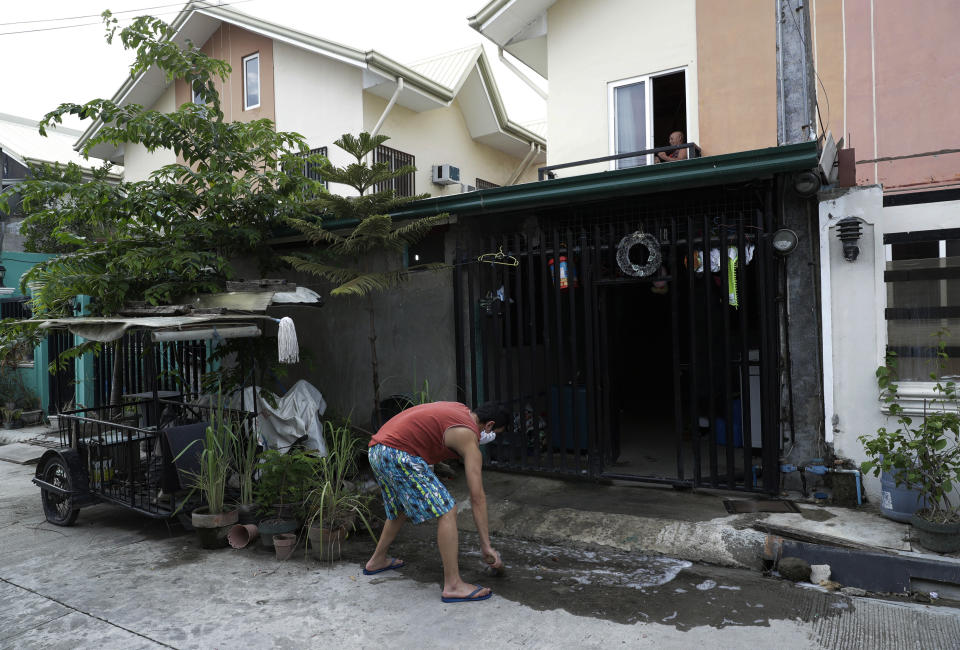 Christopher Bagay, a kitchen crew of the Aida Sol cruise ship in Europe, cleans outside his home upon arriving in Laguna province, south of Manila, Philippines Thursday, May 28, 2020. Bagay said it took him about two months to go through repetitive quarantines in Spain, Germany and Manila before he was finally allowed to go home. Tens of thousands of workers have returned by plane and ships as the pandemic, lockdowns and economic downturns decimated jobs worldwide in a major blow to the Philippines, a leading source of global labor. (AP Photo/Aaron Favila)