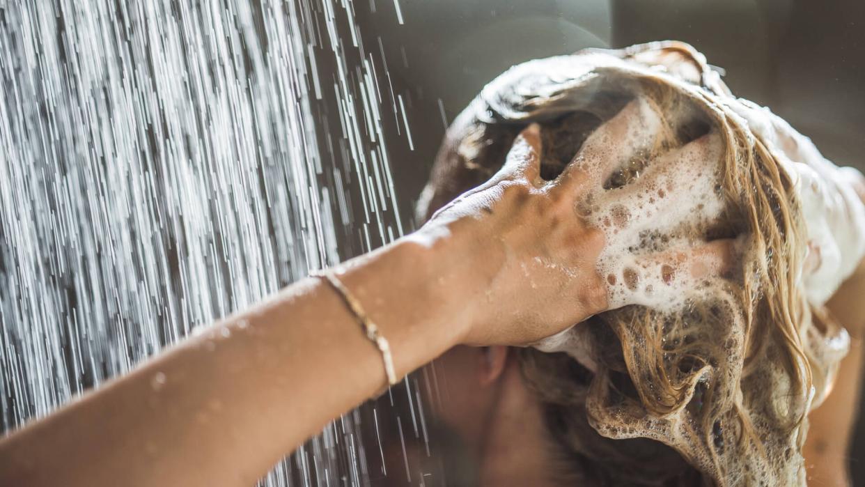 Woman washing her hair under the shower in the morning.