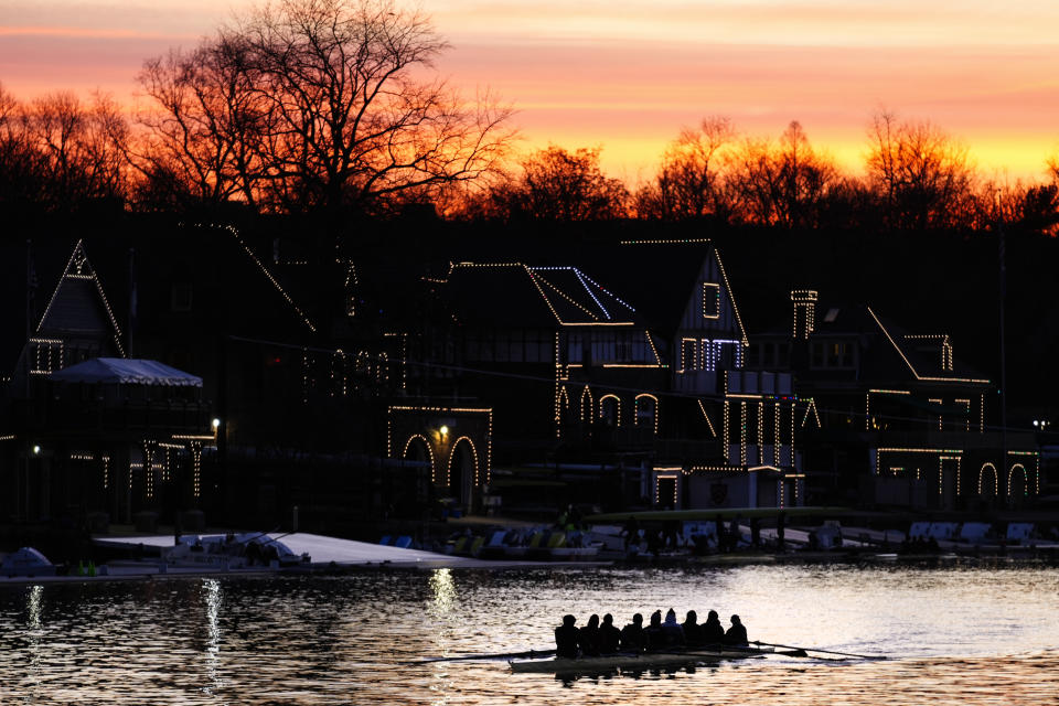 A crew sets out on the Schuylkill River as lights illuminate the outline of structures on Boathouse Row in Philadelphia, Thursday, March 16, 2023. (AP Photo/Matt Rourke)