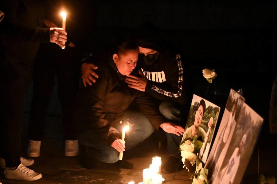 Iris Bonilla, left and her husband Osman Reyes, right, kneel at a memorial for their son, Jose Bonilla Canaca, and two other men who died when a scaffolding collapsed on a Charlotte construction site on Jan. 2. A month later, family and friends gathered at Marshall Park for a candlelight vigil in memory of the three men.
