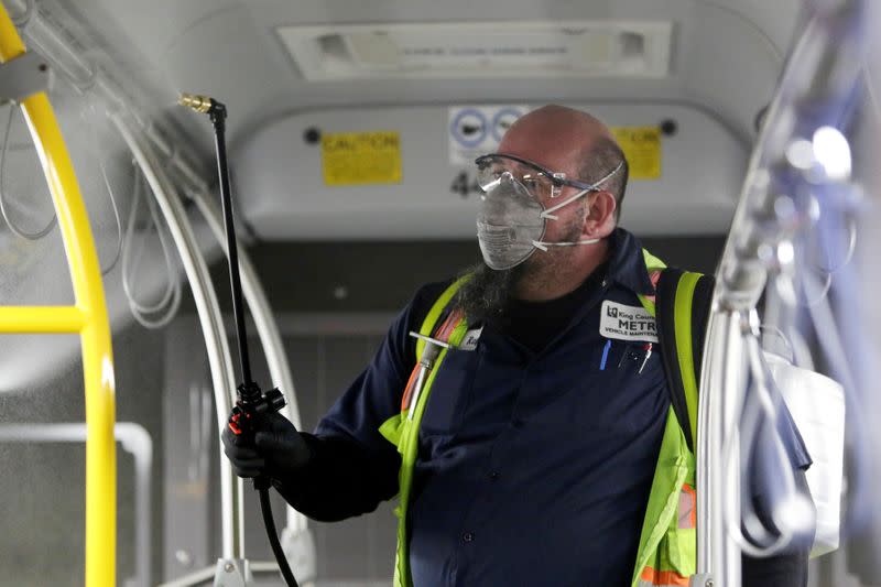 A King County Metro equipment service worker sprays a Virex solution to sanitize buses against the coronavirus in Seattle
