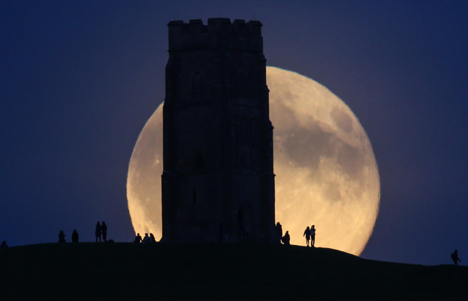 The moon rises over Glastonbury Tor in Somerset, England, on July 31.&nbsp;