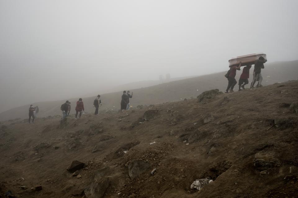 Cemetery workers carry the remains of Flavio Juarez, 50, who died of COVID-19, up the hill at the Nueva Esperanza cemetery on the outskirts of Lima, Peru, Tuesday, May 26, 2020. (AP Photo/Rodrigo Abd)