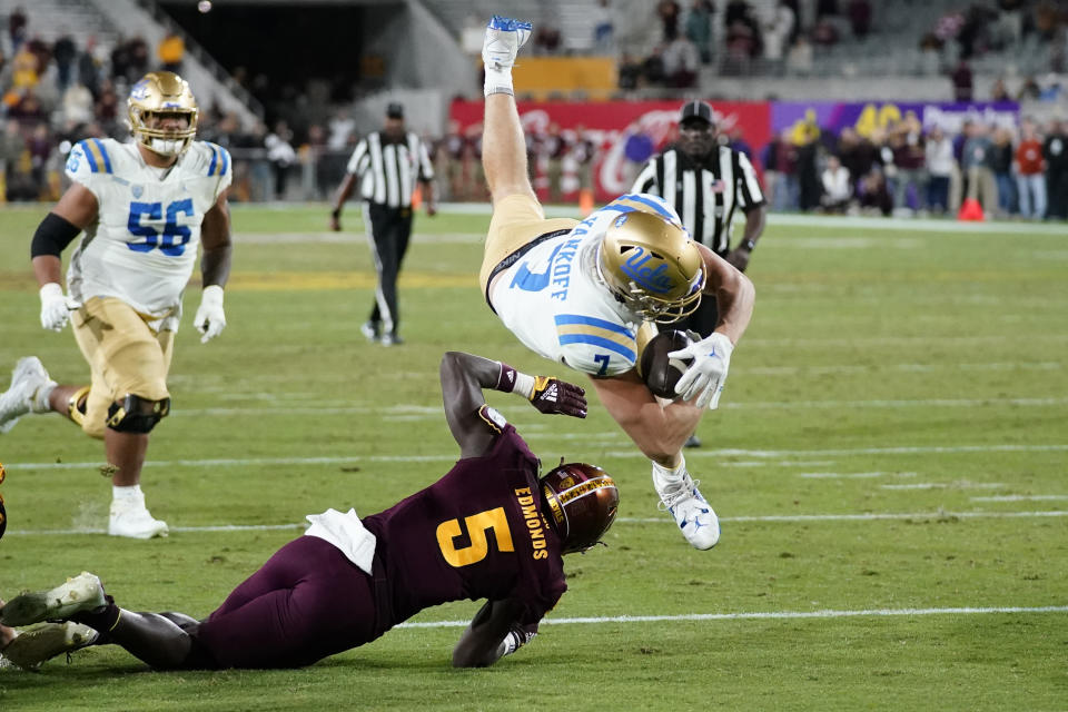 UCLA wide receiver Colson Yankoff (7) scores a touchdown as he flips over Arizona State defensive back Chris Edmonds (5) as UCLA offensive lineman Atonio Mafi (56) looks on during the second half of an NCAA college football game in Tempe, Ariz., Saturday, Nov. 5, 2022. UCLA won 50-36. (AP Photo/Ross D. Franklin)