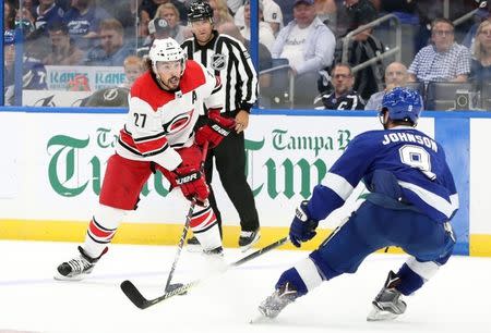 Oct 16, 2018; Tampa, FL, USA; Carolina Hurricanes defenseman Justin Faulk (27) skates with the puck as Tampa Bay Lightning center Tyler Johnson (9) defends during the first period at Amalie Arena. Mandatory Credit: Kim Klement-USA TODAY Sports