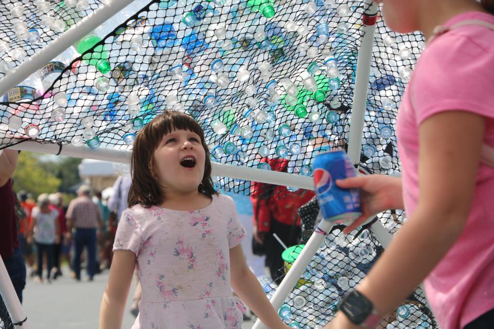 Kids in awe of "Plastic Fantastic," a 13-foot diameter geodesic dome and interactive art project made from empty plastic water bottles at the National Folk Festival Saturday, Sept. 7, 2019 in Salisbury. The bottles were donated.