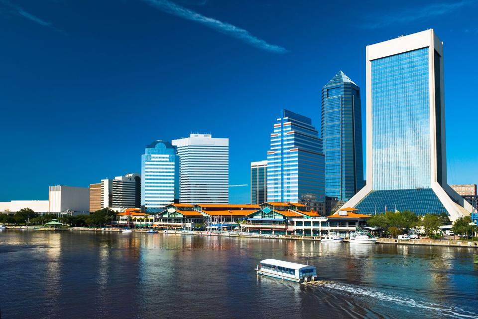 View of Downtown Jacksonville's Saint John's River waterfront skyline with a boat cruising in the foreground.