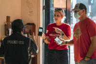 Patrons Naomi and Troy DeMontmorency, from Kern County, Calif., show their digital vaccination certificates to waiter Juan Rodrigues, left, before being allowed to enter the Fred 62 restaurant in the Los Feliz neighborhood of Los Angeles, Monday, Nov. 29, 2021. Enforcement began Monday in Los Angeles for one of the strictest vaccine mandates in the country, a sweeping measure that requires proof of COVID-19 shots for everyone entering a wide variety of businesses from restaurants to theaters and gyms to nail and hair salons. (AP Photo/Damian Dovarganes)