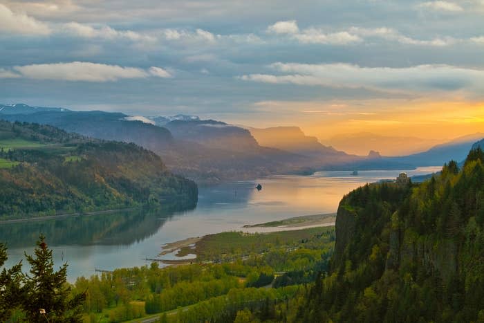 Sunrise over a river running between forested mountains