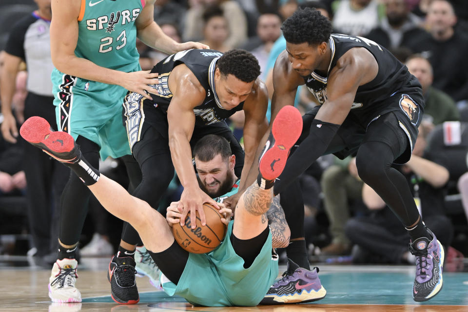 San Antonio Spurs' Sandro Mamukelashvili, bottom, fights for possession with Memphis Grizzlies' Jaren Jackson Jr., right, and Desmond Bane during the second half of an NBA basketball game, Friday, March 17, 2023, in San Antonio. (AP Photo/Darren Abate)