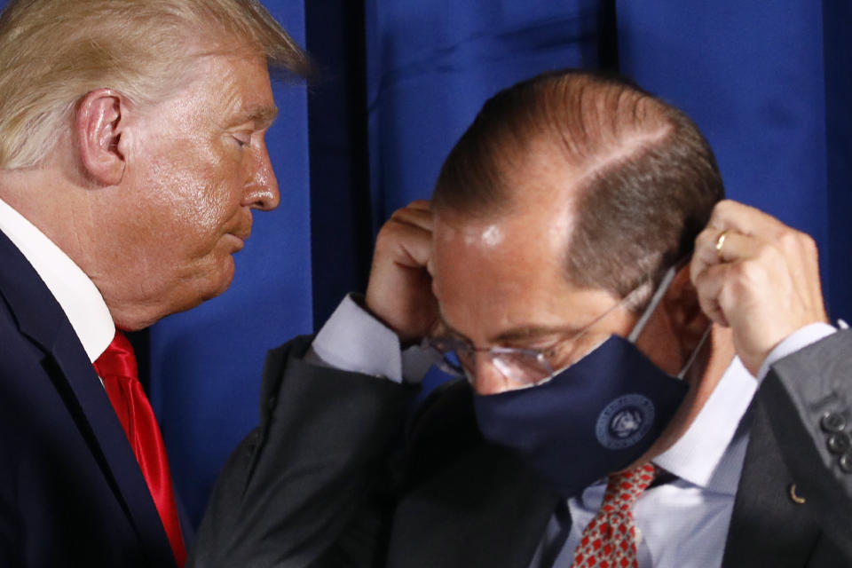 President Donald Trump departs behind Health and Human Services Secretary Alex Azar as Azar puts on a face mask to protect against the spread of the coronavirus after a roundtable discussion on the coronavirus outbreak and storm preparedness at Pelican Golf Club in Belleair, Fla., Friday, July 31, 2020. (AP Photo/Patrick Semansky)