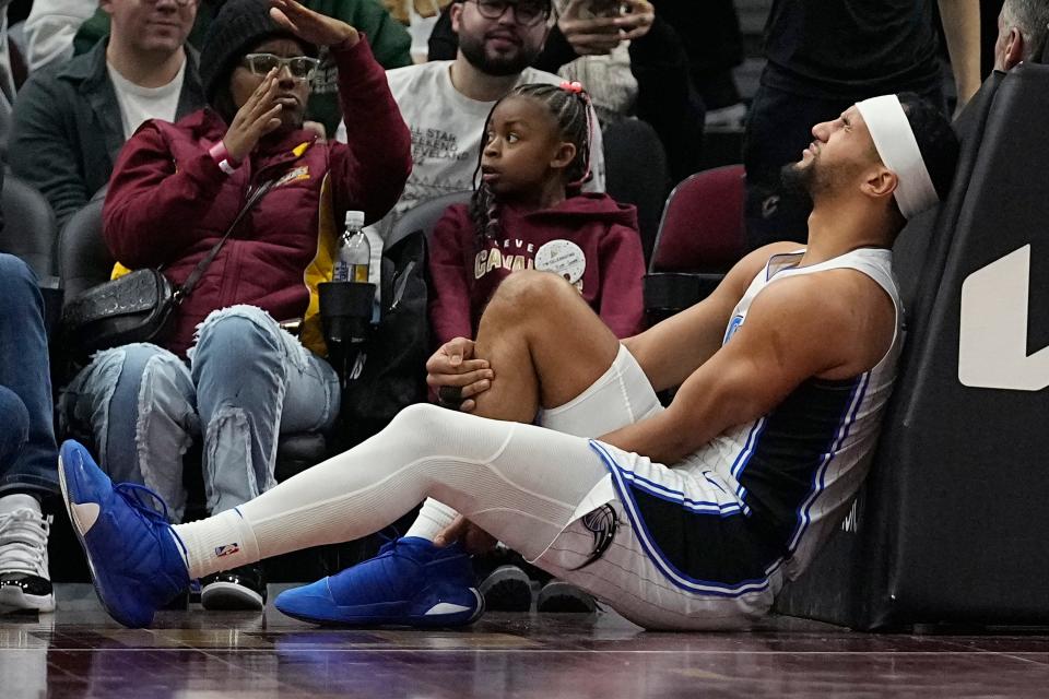 Orlando Magic guard Jalen Suggs holds his leg after being injured during the first half of the team's NBA basketball game against the Cleveland Cavaliers, Wednesday, Dec. 6, 2023, in Cleveland. (AP Photo/Sue Ogrocki)