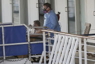 A person in a wheelchair is taken off the cruise ship Rotterdam at Port Everglades, Thursday, April 2, 2020, in Fort Lauderdale, Fla. A cruise ship that has been floating at sea with coronavirus patients aboard for two weeks after being turned away from South American ports was finally allowed to dock in Florida. The Zaandam and a sister ship sent to help it, the Rotterdam, were both given permission to disembark passengers at Port Everglades after days of negotiation with local officials who feared it would divert needed resources from a region that has seen a spike in virus cases. (AP Photo/Wilfredo Lee)