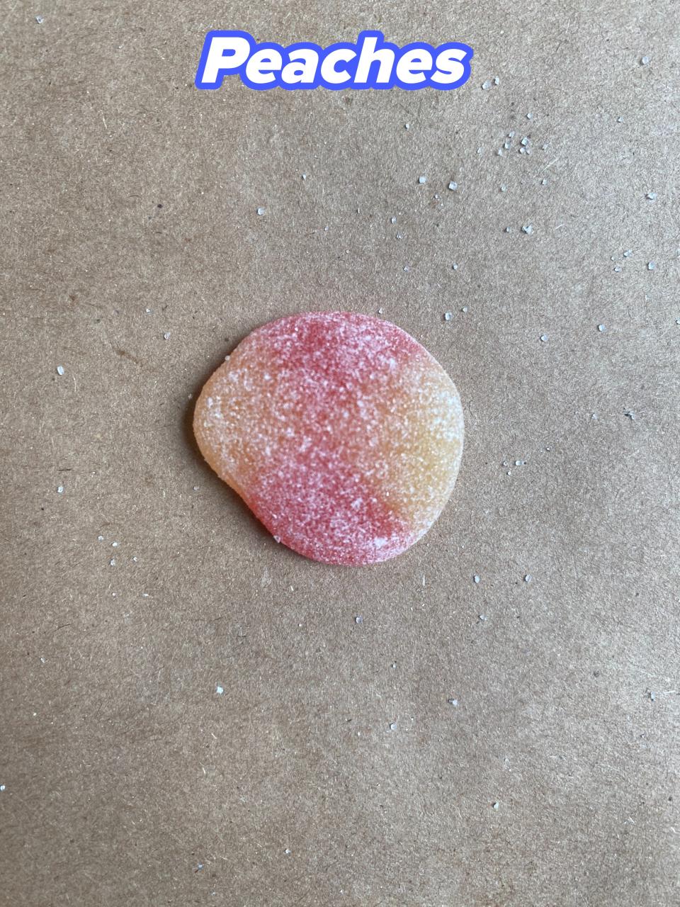 Single sugar-coated gummy candy on a plain surface