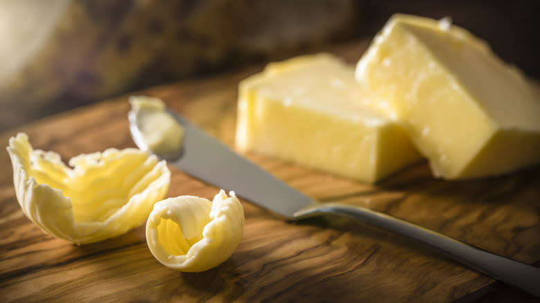 Curls and blocks of butter on wood cutting board