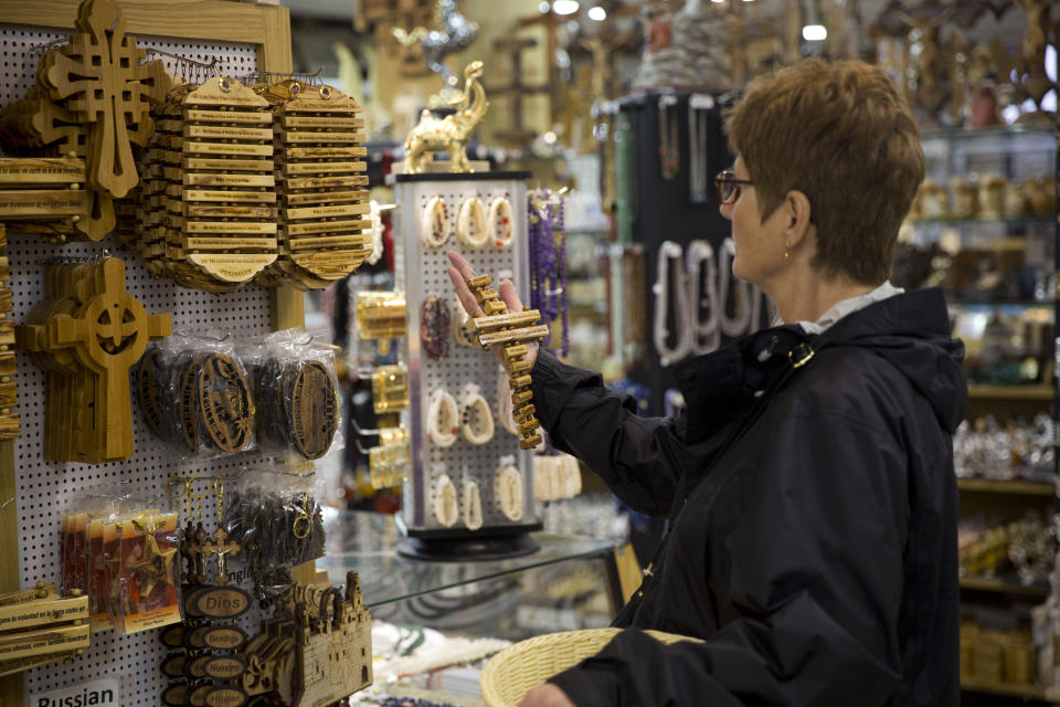 In this Thursday, Dec. 6, 2018 photo, a woman visits a shop near the Church of the Nativity, built atop the site where Christians believe Jesus Christ was born, in the West Bank City of Bethlehem. City officials are optimistic that the renovated church will help add to a recent tourism boom and give a boost to the shrinking local Christian population. (AP Photo/Majdi Mohammed)