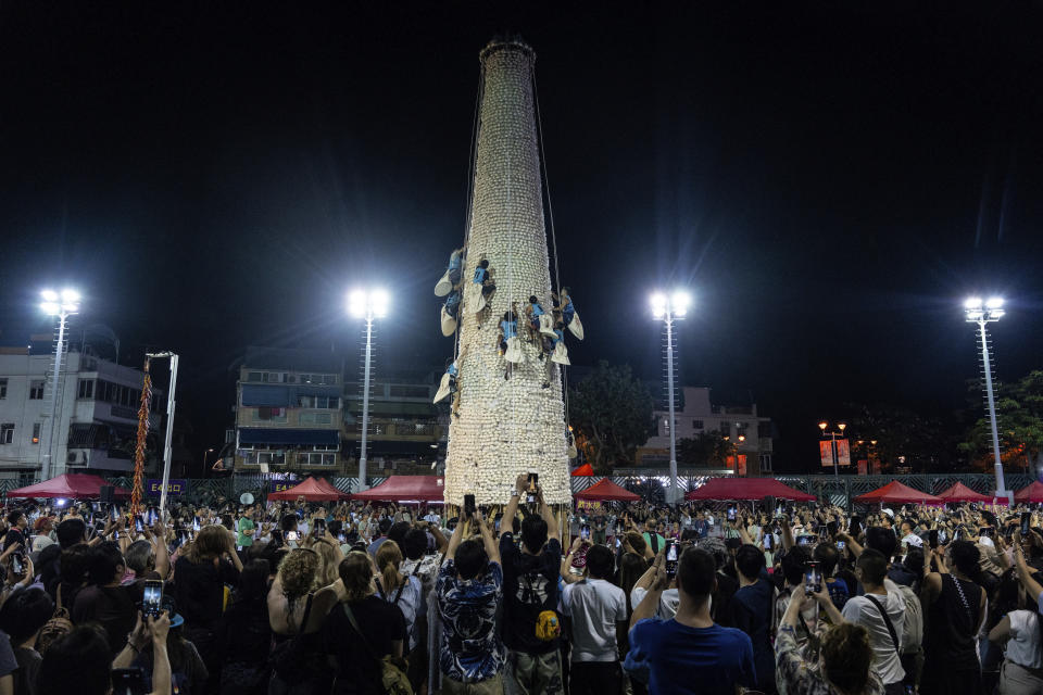 People take part in a bun scrambling competition during the Bun Festival, on Cheung Chau Island, Hong Kong, Thursday, May 16, 2024. (AP Photo/Chan Long Hei)