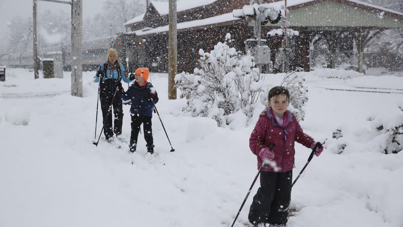 Beth Reilly, background, cross country skies with her two children, Noah, 7, in the middle, and Annelies, 5, during a snowstorm in Waterbury, Vt., on Tuesday, March 14, 2023. They were taking advantage of a snow day caused by the winter storm that was dropping heavy, wet snow across the Northeast. The storm at caused a plane to slide off the runway and led to hundreds of school closings, canceled flights and thousands of power outages in parts of the Northeast on Tuesday. (AP Photo/Wilson Ring)