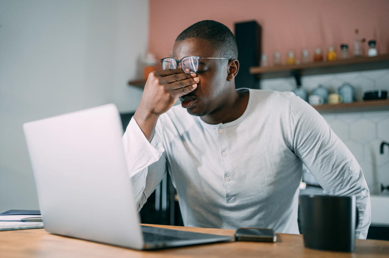 Frustrated businessman sitting on the table at home and holding his head with hand. 