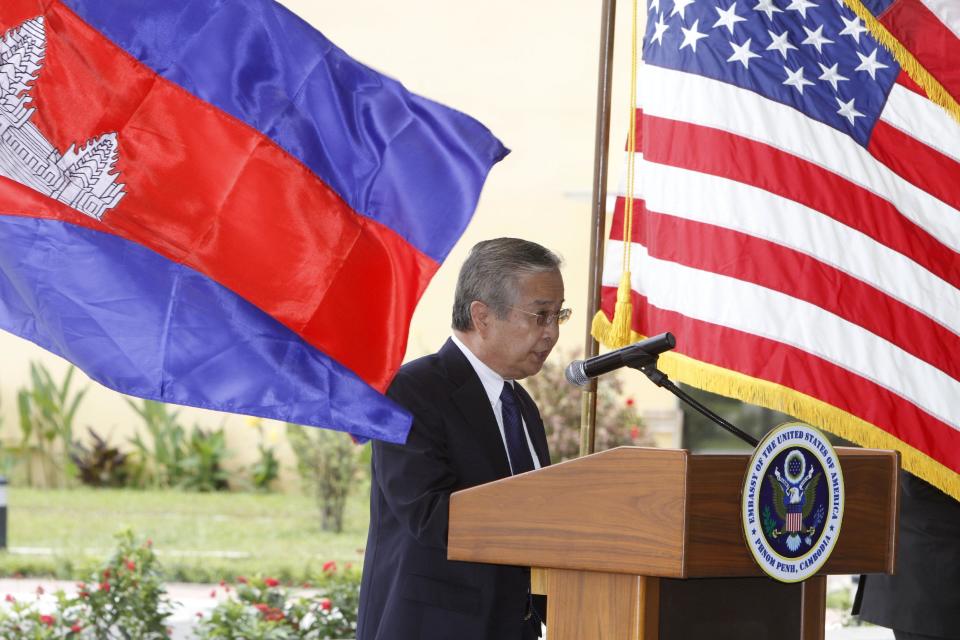 Sieng Lapresse, first vice-chairman of the Cambodia Prisoner of War/Missing in Action (POW/MIA) Committee, delivers a speech between national flags of Cambodia, left, and the United States during a repatriation ceremony to honor the recovery of possible remains of U.S. soldiers at Phnom Penh International Airport, Cambodia, Wednesday, April 2, 2014. The possible remains of U.S. soldiers found in eastern Kampong Cham province were repatriated to Hawaii for testing. (AP Photo/Heng Sinith)