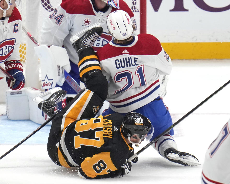 Pittsburgh Penguins' Sidney Crosby (87) and Montreal Canadiens' Kaiden Guhle (21) collide during the first period of an NHL hockey game in Pittsburgh, Saturday, Jan. 27, 2024. (AP Photo/Gene J. Puskar)