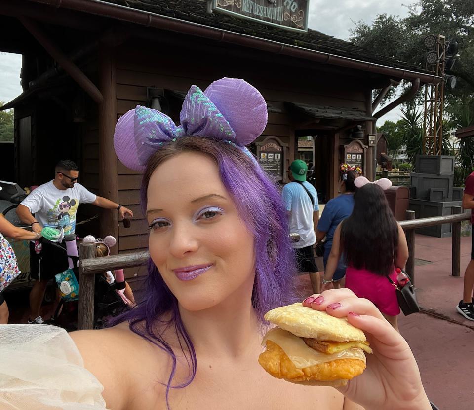 jenna posing with a biscuit breakfast sandwich in frontierland in disney world