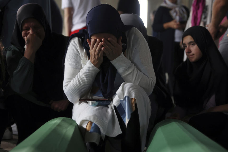 Muslim women pray next to the coffin of their relative, victim of the 1995 Srebrenica genocide in Potocari, Bosnia, Friday, July 8, 2022. The remains of the 50 recently identified victims of Srebrenica massacre, Europe’s only acknowledged genocide since World War II, arrived at the Memorial centre in Potocari where they will be buried on July 11. (AP Photo/Armin Durgut)