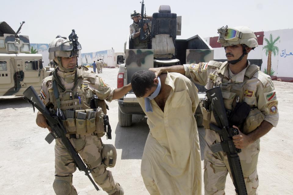 FILE - Iraqi army soldiers bring in a blindfolded and handcuffed suspected al-Qaida member to detention centers in an Iraqi army base in Baghdad, Iraq, June 16, 2010. Iraqi security forces raided some villages in Arab Jabour, south of Baghdad, and detained 16 men suspected members of al-Qaida. (AP Photo, File)