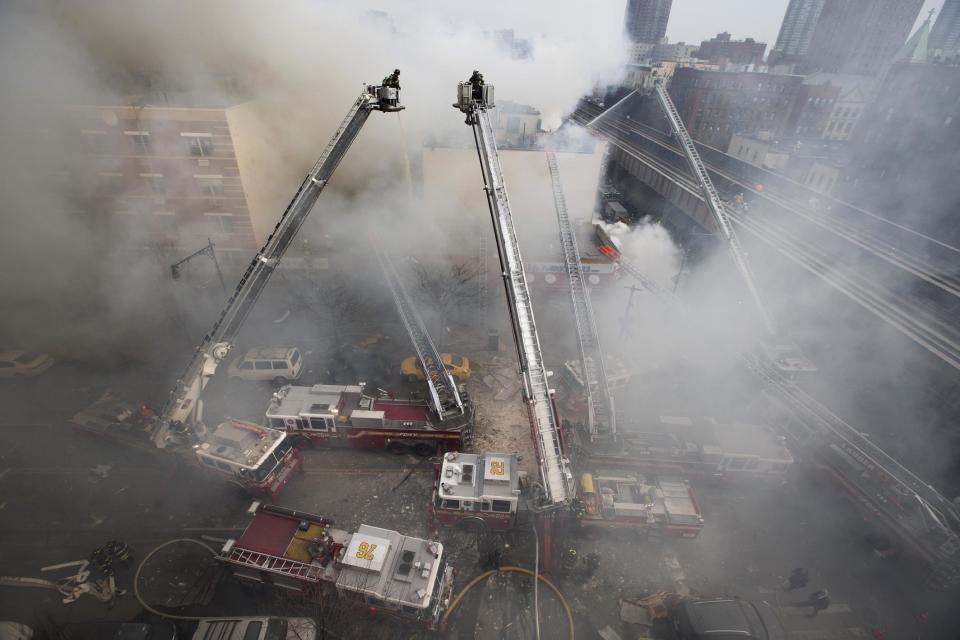 Firefighters respond to a fire on 116th Street in Harlem after a building exploded in huge flames and billowing black smoke, leading to the collapse of at least one building and several injuries, Wednesday, March 12, 2014, in New York. (AP Photo/John Minchillo)