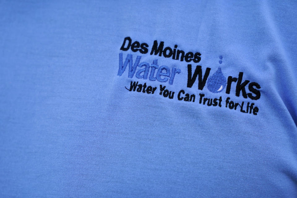 The Des Moines Water Works logo is seen on employee Bill Blubaugh's shirt as he collects a water sample from the Raccoon River, Thursday, June 3, 2021, in Des Moines, Iowa. Each day the utility analyzes samples from the Raccoon River and others from the nearby Des Moines River as it works to deliver drinking water to more than 500,000 people in Iowa's capital city and its suburbs. (AP Photo/Charlie Neibergall)