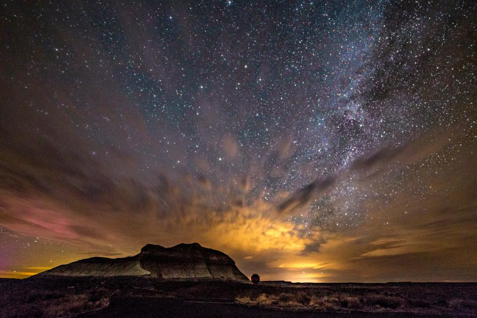 Stars peek through the clouds above The Battleship, a butte near Petrified Forest National Park's Crystal Forest.