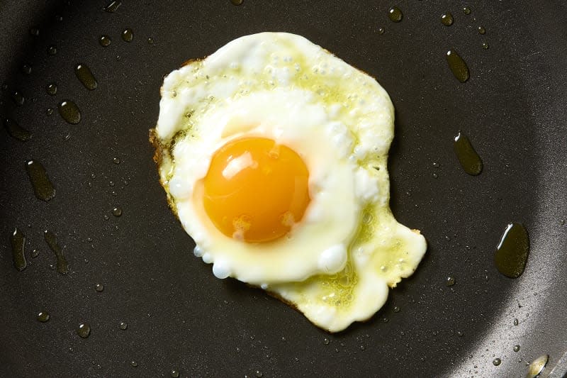 overhead shot a fried egg being cooked in olive oil