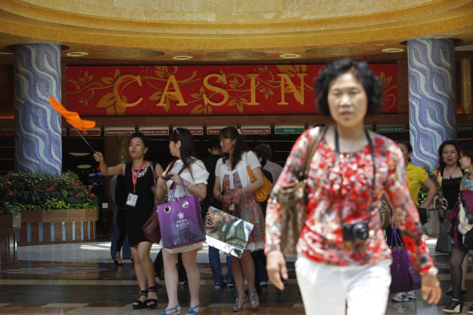 Chinese tourists arrive at the lobby of Genting Singapore's Resorts World Sentosa casino in Singapore in this April 29, 2013 file photo. Singapore's two glitzy casinos are fighting for a shrinking pool of high rolling players as China's corruption crackdown and economic slowdown reduce the number of VIPs at their tables, and the battle is starting to turn ugly. To match SINGAPORE-CASINOS/ REUTERS/Edgar Su/Files (SINGAPORE - Tags: BUSINESS POLITICS TRAVEL SOCIETY)