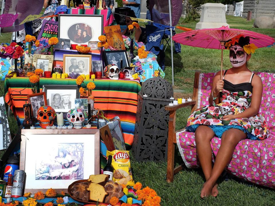 Amanda Hernandaz from the El Sereno section of Los Angeles sits by her family's grave site at the Hollywood Forever Cemetery for the Dia de los Muertos (Day of the Dead) celebration in the Hollywood section of Los Angeles on Saturday, Oct. 24, 2015. It's an ancient Mexican tradition to commemorate the dead, that year after year attracts more tourists to a cemetery that comes alive only for one night.