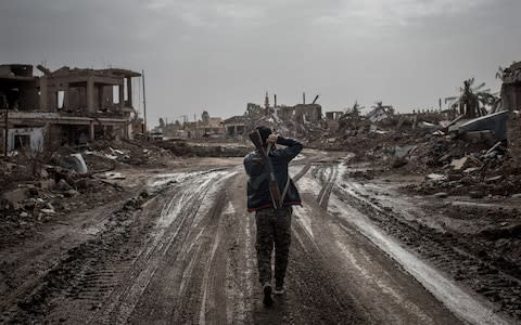 A Syrian Democratic Forces fighter walks down an empty street in As Susah, a town destroyed in fighting with Isil - Credit: &nbsp;Chris McGrath/&nbsp;Getty Images Europe