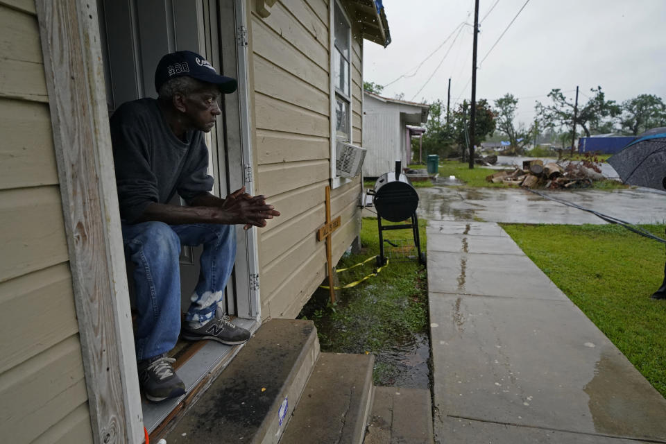 Ernest Jack, whose home was severely damaged from Hurricane Laura, sits in his front doorway as he waits for the arrival of Hurricane Delta expected to make landfall later in the day in Lake Charles, La., Friday, Oct. 9, 2020. Debris from Hurricane Laura is piled near the street. (AP Photo/Gerald Herbert)