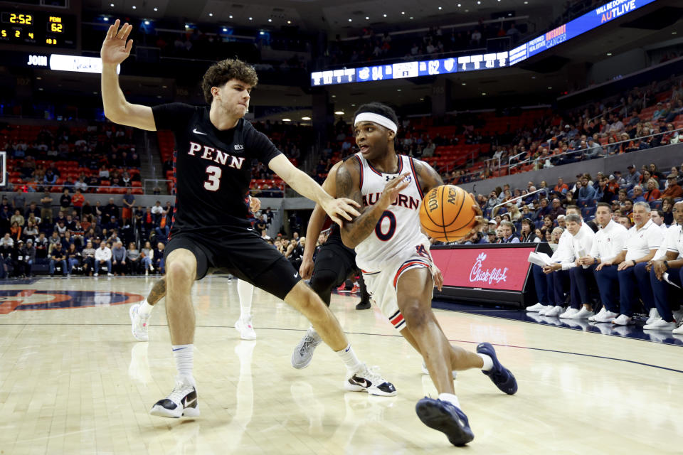 Auburn guard K.D. Johnson (0) drives the baseline around Penn forward Johnnie Walter (3) during the second half of an NCAA college basketball game Tuesday, Jan. 2, 2024, in Auburn, Ala. (AP Photo/Butch Dill)