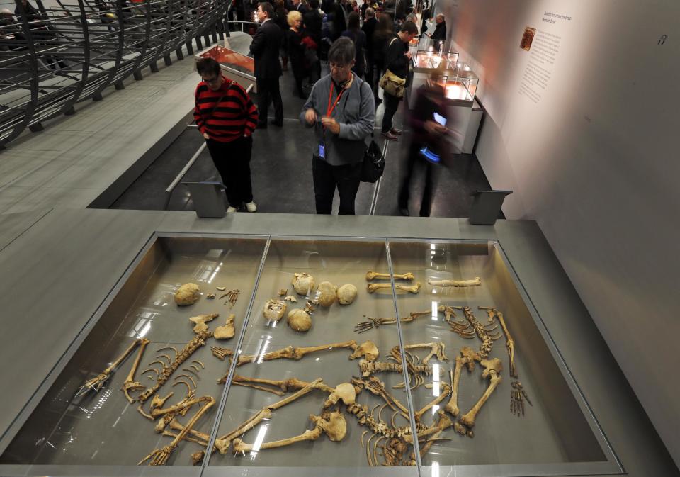 Visitors look at some of the 50 headless skeletal remains of young men found in a mass grave on England's south coast, apparently a Viking raiding party that failed, at a new exhibition entitled 'Vikings: Life and Legend' at the British Museum in central London, Tuesday, March 4, 2014. The new exhibition strives to make people think again about the Scandinavian pillagers who raided and struck terror into English villages. The exhibition aims to show how Viking energy and ideas re-drew the map of the world, through the presentation of their ships, their weapons, their crafts, their words and even their skeletons. (AP Photo/Lefteris Pitarakis)