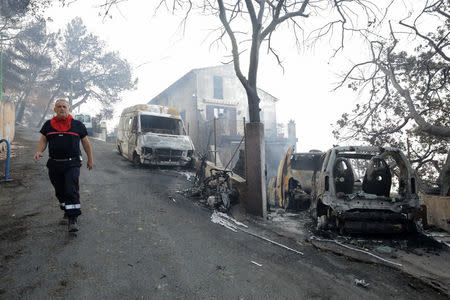 A fireman walks past vehicles that were destroyed by a burning wildfire in Carros, near Nice, France, July 24, 2017. REUTERS/Eric Gaillard