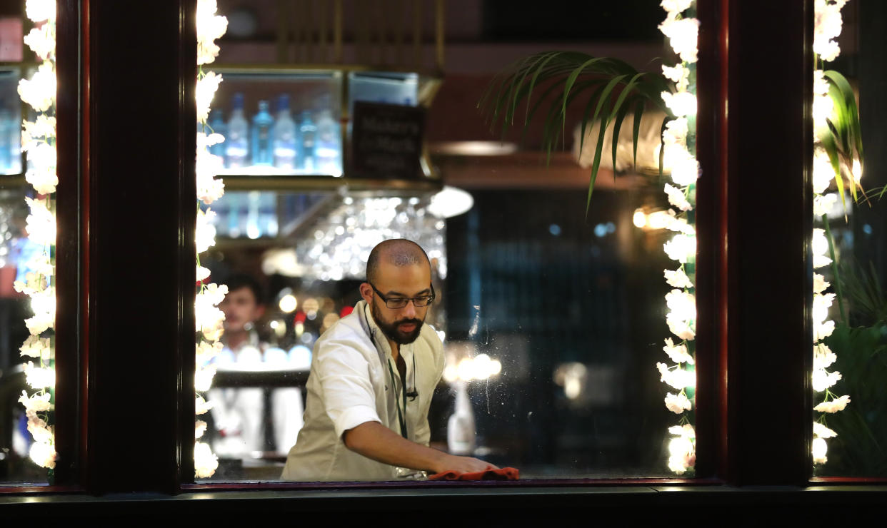 A barman at the Seven Stars pub in Brighton cleans the bar area after closing as from today pubs and restaurants will be subject to a 10pm curfew to combat the rise in coronavirus cases in England.