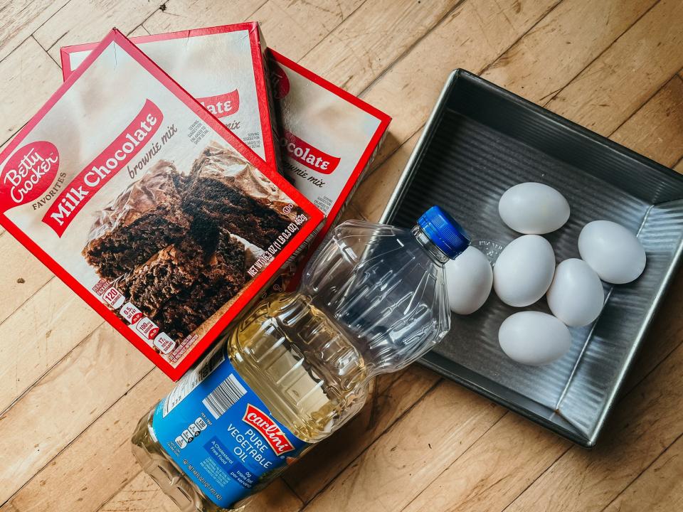 three boxes of brownie mix, a bottle of oil, and six eggs ina. pan