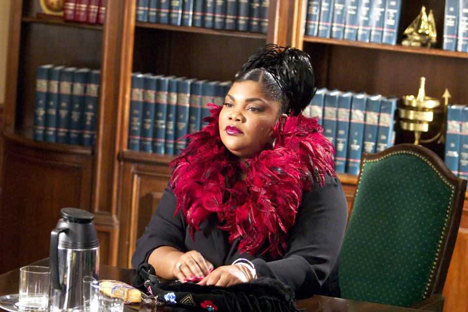 Mo'Nique in a law office scene, wearing a dramatic feather boa