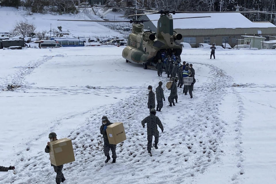 In this photo provided by Japanese Ministry of Defense, members of Japan Self-Defense Forces carry relief goods in the earthquake-hit city Wajima, Ishikawa prefecture, Japan Monday, Jan. 8, 2024. (Japanese Ministry of Defense via AP)