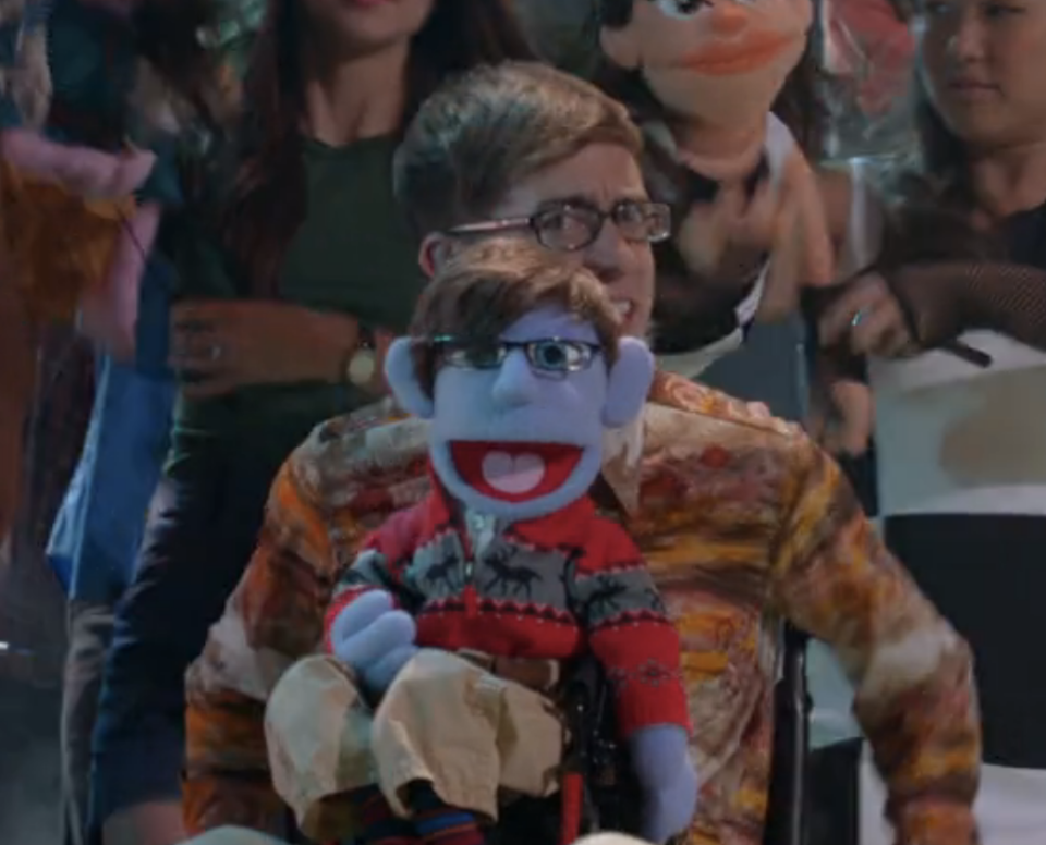 kevin's character looking at the camera while a toy version of himself sits on his lap
