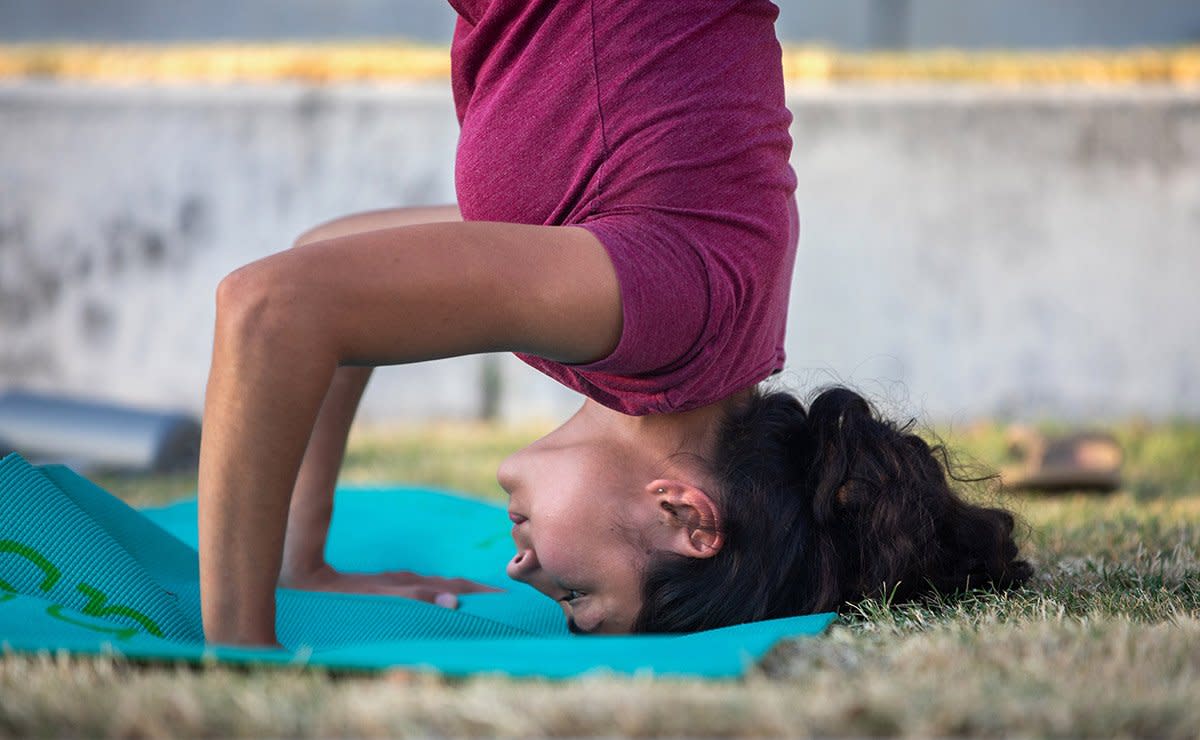 A young woman does a yoga headstand.