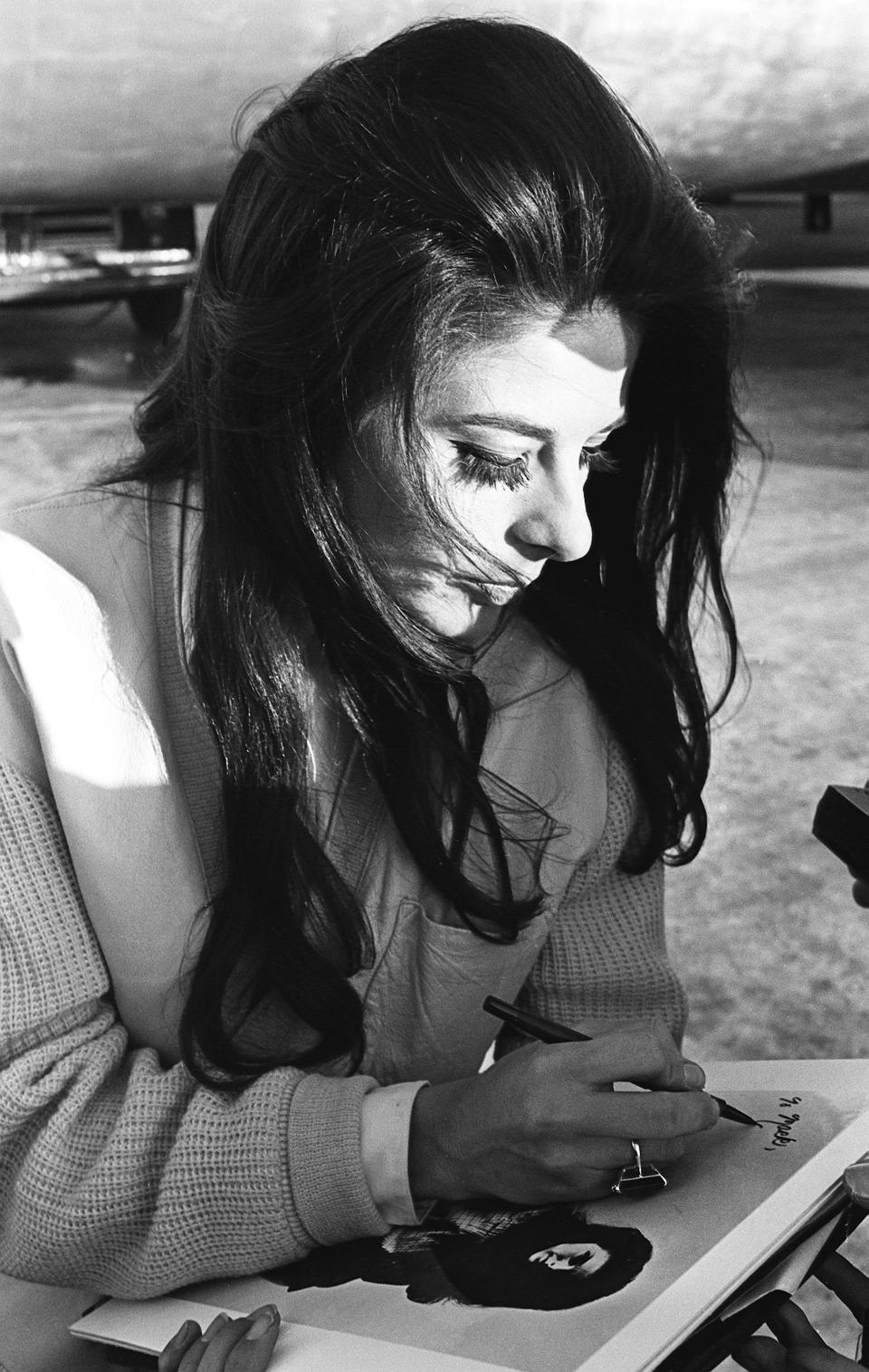 Singer Bobbie Gentry signs her autograph outside the airport in Nashville in 1967.