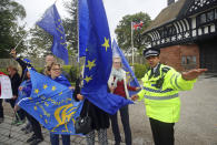 A police officer talks to anti-Brexit protesters outside the entrance to Thornton Manor, in The Wirral, England, Thursday Oct. 10, 2019. Britain's Prime Minister Boris Johnson and Irish couterpart Leo Varadkar are meeting at Thornton Manor Thursday in a bid to break the Brexit deadlock. (Danny Lawson/PA via AP)
