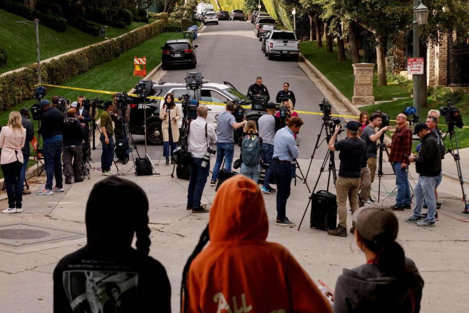 Media members work as law enforcement officers stand behind police tape outside a property connected to hip-hop star Sean "Diddy" Combs.